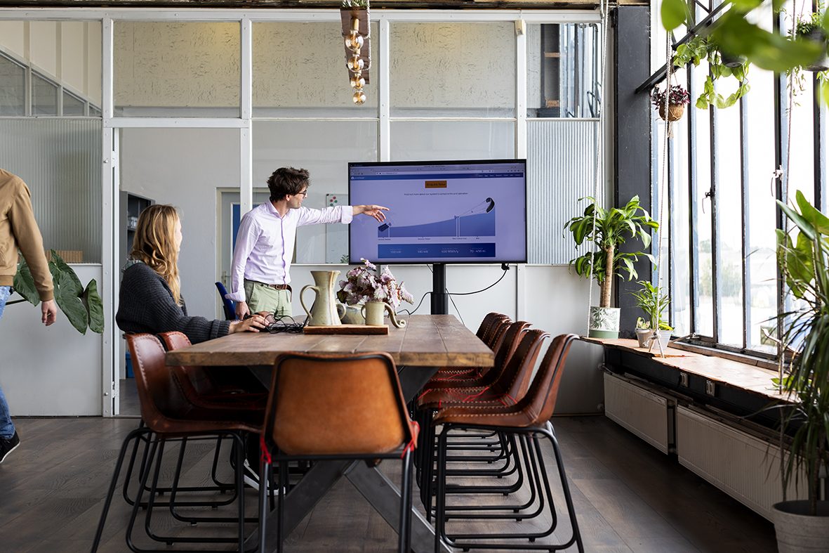 Two engineers working through a system diagram on a screen in a meeting room